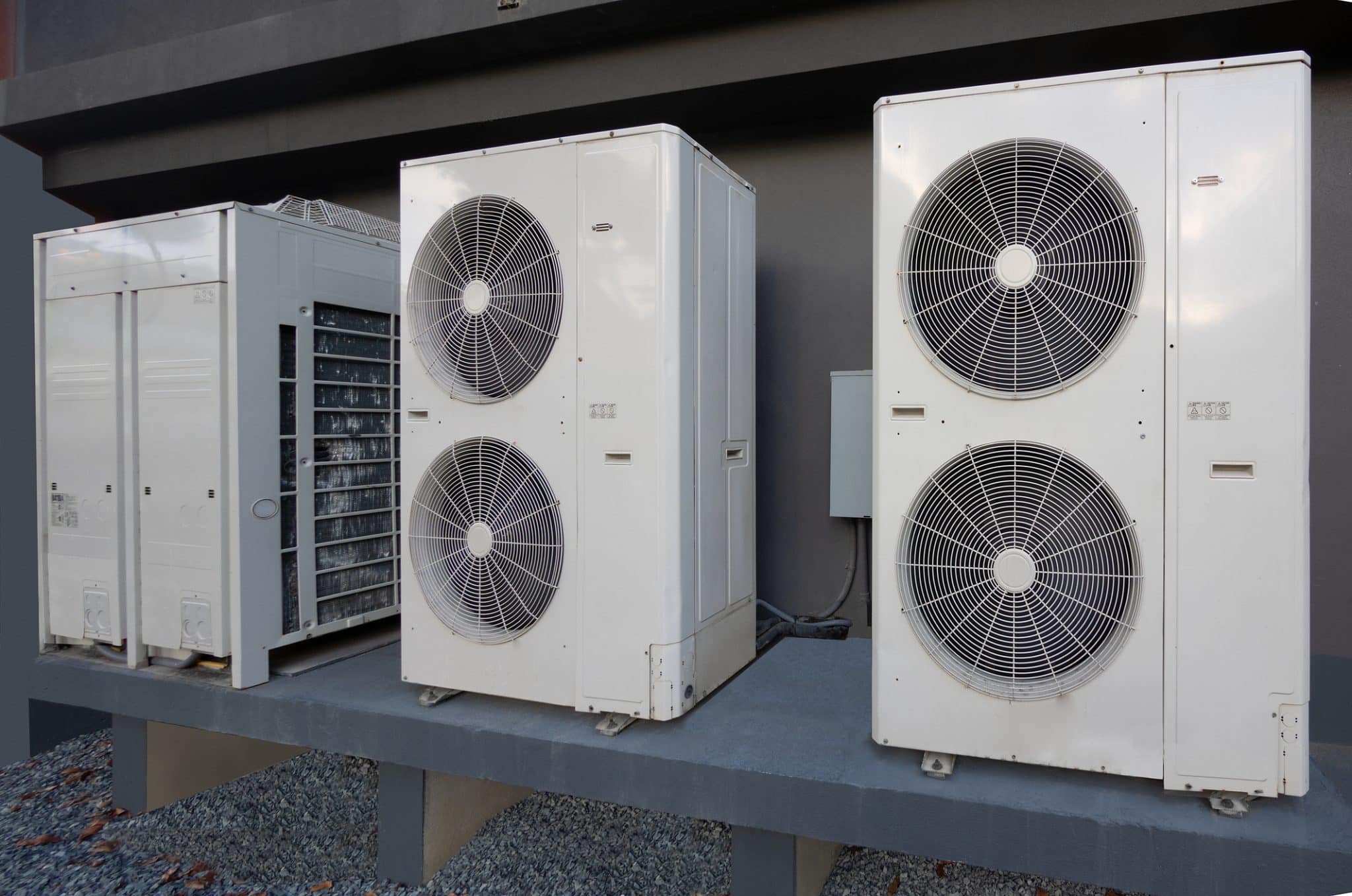 High-efficiency modern central air unit next to a heat pump cooling unit outside of an apartment complex.